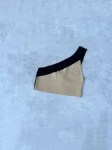 Top corto de tejido de punto, con diseño asimétrico de un solo hombro. La parte principal es de color lila y el tirante es de color naranja.