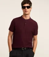 Remera polo de hombre en color bordó, de corte slim, confeccionada en tejido de piquet texturizado. Cuenta con cuello tipo mao con pequeña abertura y cierre frontal de dos botones, y mangas cortas.
