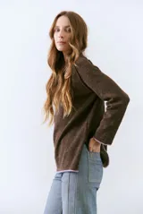 Buzo de tejido de punto color beige, con corte relajado, cuello redondo y mangas largas. Presenta detalles de terminaciones en color azul marino en los puños y en el ruedo inferior.