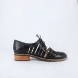 Zapato Oxford negro con cordones, capellada de cuero con textura croco y cortes calados. Taco bajo foliado y suela de goma antideslizante.