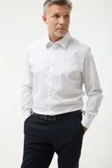 Camisa blanca con pequeños estampados geométricos azules, de corte clásico y manga larga.
