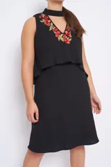 Vestido negro sin mangas con bordado de flores en hilo de seda color coral y dorado en el escote.