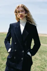 Blazer de pana azul marino con diseño cruzado, cuello solapa, hombreras marcadas y cierre frontal con botones. Cuenta con bolsillos delanteros con solapa y abertura en la espalda.