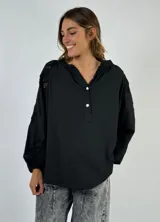 Blusa negra de mangas largas con detalle de encaje en hombros y mangas, cuello en V y cierre frontal con botones.