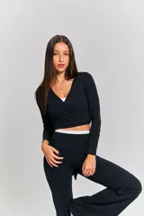 Top deportivo negro de manga larga con diseño envolvente y tiras largas para anudar en la cintura.