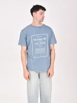 Remera color beige con estampa rectangular con diseño abstracto en tonos marrones y texto.