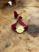 Pulsera dorada con dije redondo con la imagen de la Virgen de Fátima y cinta de terciopelo elástico color verde petróleo.