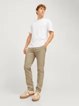 Pantalón chino slim de tiro medio color beige, con cierre de cremallera y bolsillos laterales.
