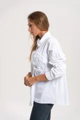 Camisa de pana blanca con cuello clásico, cierre frontal de botones y aplicaciones florales en relieve en el frente.