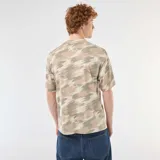 Remera de algodón con cuello redondo y estampado de camuflaje en tonos verde militar, beige y marrón, de corte relajado y mangas cortas.
