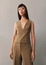 Chaleco de corte recto y diseño minimalista, con escote en pico profundo y tirantes anchos. Presenta un estilo sastrero sin mangas, ideal para combinar en conjuntos formales.