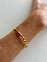 Pulsera dorada rígida con forma de caña de bambú.