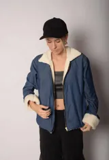 Campera azul de jean con interior de corderito blanco, cierre frontal y bolsillos laterales.