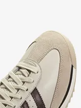 Zapatillas Adidas modelo SL 72, con diseño retro en tonos crema y marrón. Presentan una base de cuero con superposiciones de gamuza, las icónicas tres tiras laterales en marrón y una mediasuela de EVA con suela de caucho dentada.