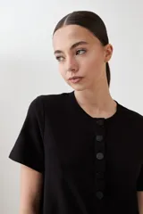 Vestido midi negro de corte recto, con cuello redondo y botones frontales.