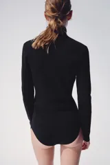 Chaqueta de punto negra con cuello subido y cierre frontal con cremallera, de manga larga y diseño ajustado.