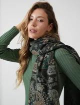 Bufandón de tejido soft, marca Adrienne Vittadini, con estampado de arabescos en tonos verde, beige y negro. Presenta terminación con flecos.