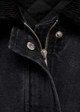 Chaqueta estilo vaquero de algodón en color negro lavado, con diseño oversize y acolchado interior. Presenta cuello camisero en contraste, cierre frontal con botones a presión, dos bolsillos de parche con solapa y dos bolsillos de ribete en la parte delantera.