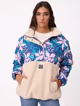 Campera tipo canguro con diseño combinado, parte superior estampada con flores en tonos azules y rosados, y parte inferior de tejido sherpa en color beige. Cuenta con cuello alto, cierre frontal parcial y bolsillo tipo canguro delantero con logo de la marca.