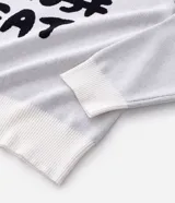 Suéter de corte boxy confeccionado en tejido jacquard de viscosa y poliéster. Presenta cuello redondo, mangas largas y un diseño estampado con lettering en color negro sobre fondo blanco.