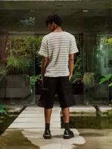 Remera de tejido de punto abierto, color crudo y beige, con diseño de rayas horizontales finas. Presenta cuello redondo y mangas cortas.