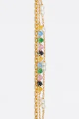 Pulsera de triple cadena dorada con dijes de corazones de cristal en diversos colores y perlas blancas. Posee cierre de mosquetón y cadena ajustable.
