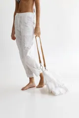 Pantalón babucha blanco de lino con bordados florales, pretina combinada con cierre y botón en el frente y elástico ancho en la espalda, ajuste en los tobillos con tiras y bolsillos aplicados.