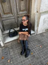 Conjunto compuesto por un remerón negro de algodón con estampa fotográfica frontal y una pollera midi de satén con estampado animal print de leopardo.