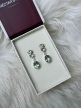Caravanas colgantes de plata 950 con diseño de textura orgánica e irregular en la parte superior y piedra facetada ovalada de praisiolita (cuarzo verde) colgante. Cierre de perno y tope.
