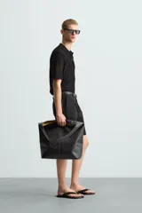 Polo de manga corta color negro, con cuello solapa y cierre frontal de botones. Confeccionado en tejido de punto con estructura abierta y calada.