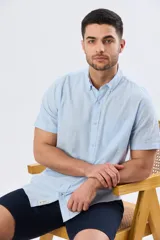 Camisa de manga corta confeccionada en mezcla de lino y algodón, color beige, con cuello camisero abotonado, bolsillo frontal en el pecho y cierre de botones.