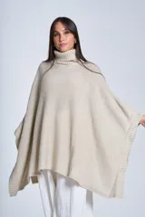 Poncho tejido color beige, con cuello alto y corte asimétrico.