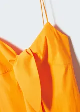 Vestido corto de tirantes finos, color amarillo, con escote recto y detalle de nudo frontal. Presenta un diseño ajustado y cierre lateral con cremallera.