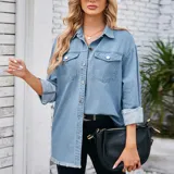 Campera tipo sobrecamisa de denim en tono azul claro, con corte oversize, cuello italiano, cierre frontal con botones metálicos, bolsillos frontales con solapa y ruedo con detalle desflecado.