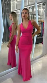 Vestido largo ajustado color fucsia con escote pronunciado en V y espalda descubierta con tiras finas cruzadas.