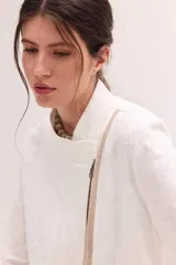 Chaqueta de lino lavado color blanco, con cuello mao, cierre metálico diagonal y detalles en contratono.