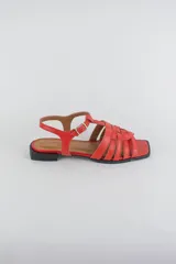 Sandalias de cuero color negro, de suela plana, con tiras entrelazadas en la capellada y tira ajustable en el talón con hebilla metálica.