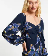 Vestido corto de viscosa y lino con estampado de mariposas, escote en pico y mangas largas abullonadas.