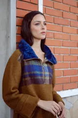 Buzo marrón de lana con mangas rectas, largo medio y cuello con cierre. Aplique de corderito azul en el cuello. Buzo amplio con diseño a cuadros en la parte superior.