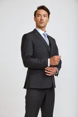 Traje de tres piezas compuesto por saco, chaleco y pantalón de corte sastre. El conjunto presenta un diseño en color gris oscuro con un sutil patrón de cuadros gales, ideal para eventos formales.