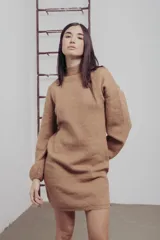 Vestido corto de punto color fucsia, con cuello alto y mangas largas amplias. Diseño holgado y cómodo.