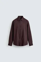 Camisa blanca de manga larga con cuello italiano y cierre frontal de botonadura. Corte regular fit.