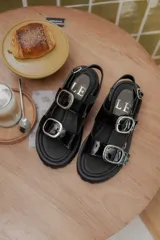 Sandalias negras de charol con plataforma y hebillas plateadas.