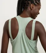 Musculosa deportiva de corte nadador, color amarillo claro, confeccionada en microfibra con textura perforada. Presenta escote en U y diseño holgado con pliegue en la espalda.