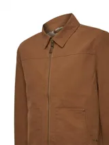 Chaqueta de canvas color marrón, con cierre frontal completo, cuello clásico y forro interior de sherpa. Presenta dos bolsillos frontales tipo parche y corte regular.