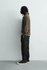 Pantalón cargo de corte slim fit en color negro, confeccionado en tejido de algodón con elasticidad. Presenta cintura elástica ajustable con cordón, bolsillos laterales tipo cargo con solapa y bajo acabado en puño elástico.
