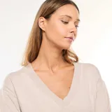 Sweater de punto fino en color beige, con escote en pico, manga larga y puños acanalados.