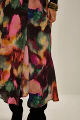 Falda midi de viscosa con estampado abstracto multicolor en tonos vibrantes como fucsia, violeta, verde y naranja. Presenta un diseño fluido con una abertura frontal que permite mayor movimiento.