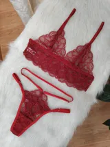 Conjunto de lencería de encaje color rojo, compuesto por un bralette triangular sin aro y una tanga con tiras laterales ajustables.