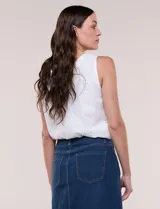 Blusa blanca sin mangas de calce holgado, confeccionada en tejido liviano con bordado estilo broderie. Presenta escote bote y ruedo inferior elastizado que genera un sutil efecto abullonado.